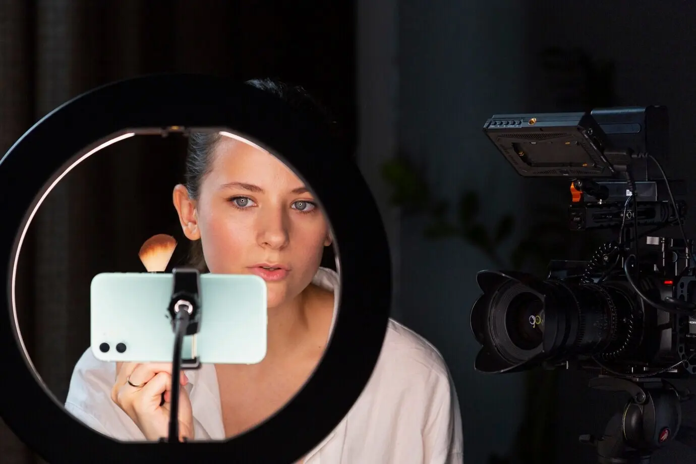 Молодая женщина снимает влог о макияже на свой смартфон.